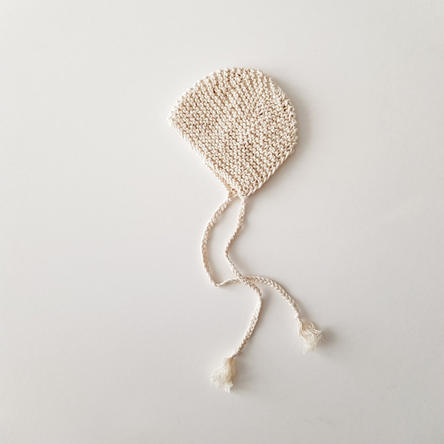 Knitted bonnet for baby doll, natural white